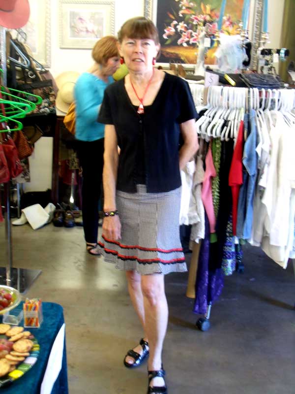 Ann, in black and white skirt, trimmed in red and black, and black top. The red is brought out by a bright red fused glass pendant and matching earrings.